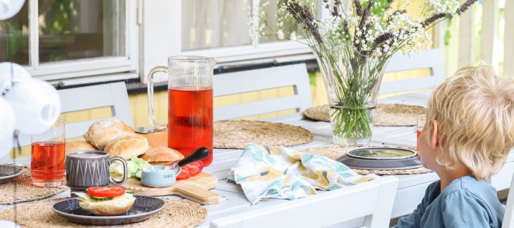 Bild som visar en liten pojke sittandes vid uppdukat frukostbord med nybakade kalljästa frallor.