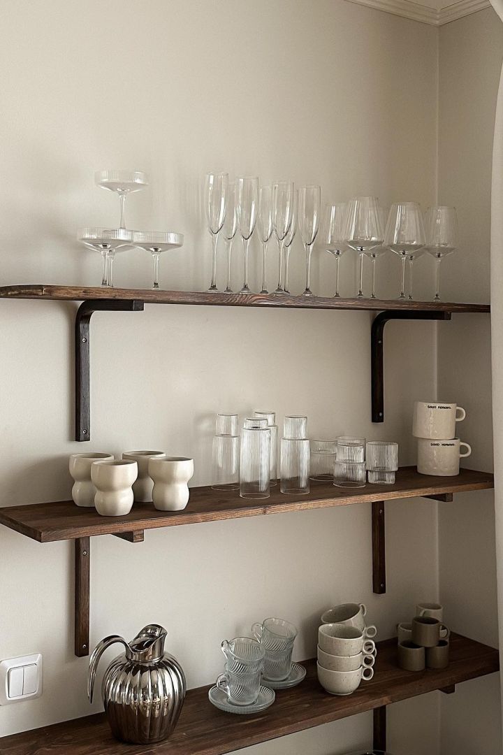 En hylla med glas och koppar i närheten av kaffebaren är också en bra idé. Här kan du se en hylla i tre nivåer med Limfjord-muggarna från Broste Copenhagen, olika Ripple-glas från ferm LIVING och Freckle-muggarna från Scandi Living i köket hos den svenska influencern Joanna Avento.