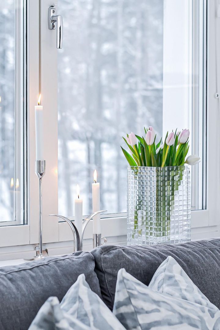 Dekorera din fönsterbräda med ljus eller vackra blommor, särskilt under de mörkare månaderna. Här kan du se färska tulpaner i vasen City Hurricane av Louise Roe, bredvid olika silverljusstakar med vita ljus i på fönsterbrädan av @josefinsinredning.