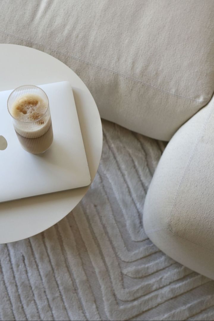 Här kan du se en perfekt tillagad latte macchiato i ett long drink-glas från Ripple-kollektionen från Ferm Living, som står på ett soffbord bredvid en beigefärgad soffa i @ellesklingens hem.