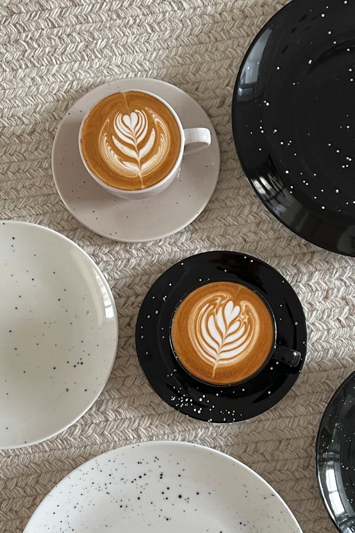 Två koppar konstfullt arrangerat kaffe i svart och beige från Scandi Livings Freckle-kollektion omgivet av tallrikar i @Avery-P:s hem.